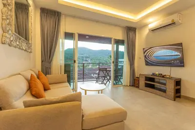 a living room with a couch and a television at C126 Walk to Beach Global & Local Eats Pool & Gym in Rawai Beach