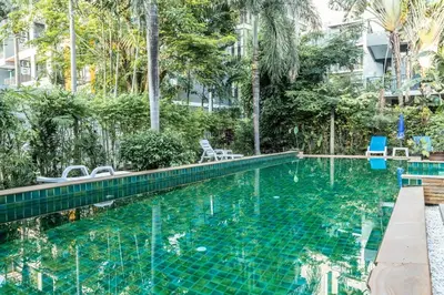 a swimming pool at a resort with chairs and trees at C126 Walk to Beach Global & Local Eats Pool & Gym in Rawai Beach