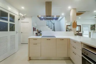 a large kitchen with white cabinets and a staircase at Koson Elegant 3 Bedroom Villa in Rawai Beach