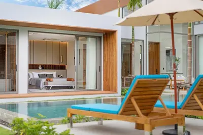a pair of chairs and an umbrella next to a swimming pool at Zenithy Morden Pool and Garden Villa near Bangtao Beach in Ban Pak Lak