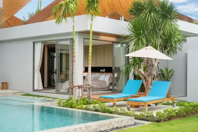 a villa with a swimming pool and two chairs and an umbrella at Zenithy Morden Pool and Garden Villa near Bangtao Beach in Ban Pak Lak