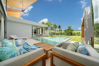 an outdoor patio with two couches and a swimming pool at Zenithy Morden Pool and Garden Villa near Bangtao Beach in Ban Pak Lak