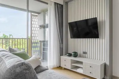 a living room with a couch and a television on a wall at The Ozone Lounge Lovers Golf View Bangtao in Laguna Phuket