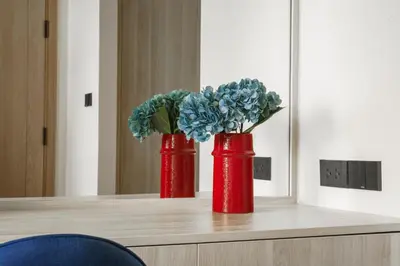 two red vases with blue flowers on a table at The Ozone Catisse Golf View Bangtao in Laguna Phuket