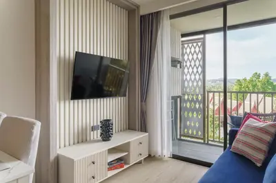 a living room with a tv and a balcony at The Ozone Catisse Golf View Bangtao in Laguna Phuket