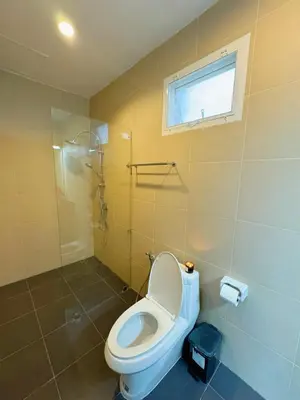 a bathroom with a toilet and a window at shine bright villa in Ban Saiyuan (1)