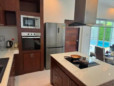 a kitchen with wooden cabinets and stainless steel appliances at shine bright villa in Ban Saiyuan (1)