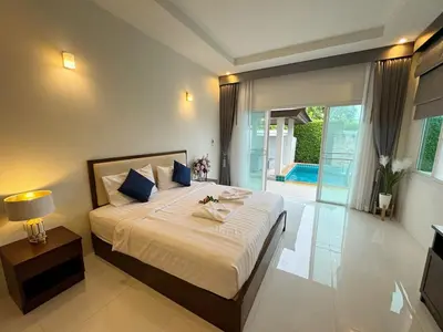 a bedroom with a large bed with white sheets and blue pillows at shine bright villa in Ban Saiyuan (1)