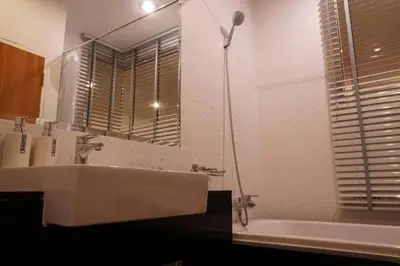 a bathroom with a sink and a tub and a mirror at A Well Equipped Condo near Karon Beach in Karon Beach