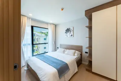 a bedroom with a bed and a large window at RJ Space in Ban Thalat Choeng Thale