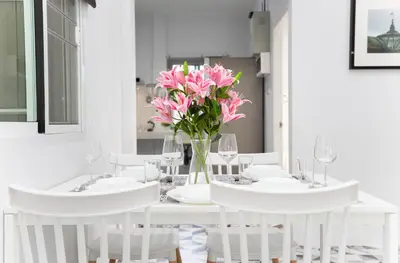 a white dining room with two white tables and pink flowers at Seaside house in Ban Thalat Choeng Thale