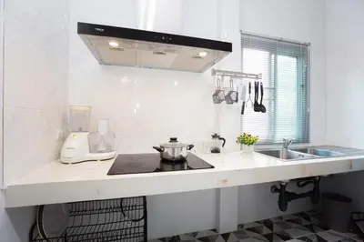 a white kitchen with a sink and a stove at Seaside house in Ban Thalat Choeng Thale
