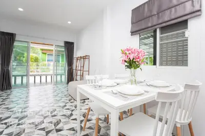 a white dining room with a white table and chairs at Seaside house in Ban Thalat Choeng Thale