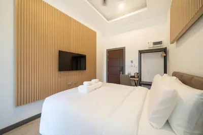 a bedroom with a white bed and a flat screen tv at DC Resident Phuket in Phuket Town