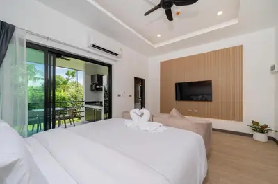 a bedroom with a large white bed and a tv at DC Resident Phuket in Phuket Town