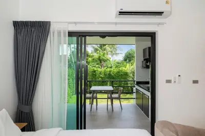 a room with a balcony with a bed and a table at DC Resident Phuket in Phuket Town