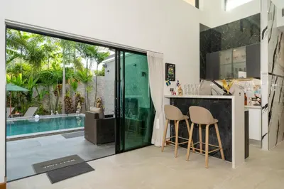 a kitchen with a bar and a swimming pool at Noi's Villa - tropical oasis with pool and maid in Kamala Beach
