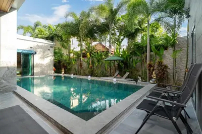 a swimming pool with a chair next to a house at Noi's Villa - tropical oasis with pool and maid in Kamala Beach