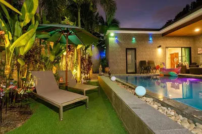 a pool with chairs and an umbrella next to a house at Noi's Villa - tropical oasis with pool and maid in Kamala Beach