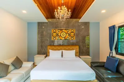 a bedroom with a bed and a couch and a chandelier at Noi's Villa - tropical oasis with pool and maid in Kamala Beach