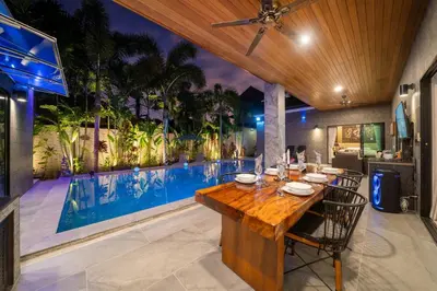 an outdoor dining room with a table and a swimming pool at Noi's Villa - tropical oasis with pool and maid in Kamala Beach