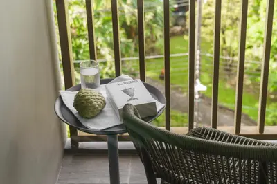 a table with a book and a drink on a balcony at The Ozone Terracotta Art Golf View Bangtao in Laguna Phuket