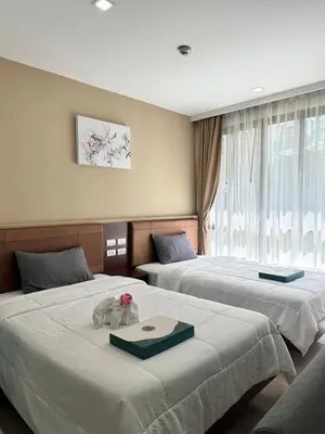a hotel room with two beds with flowers on them at Condominium Royal Lee Airport Phuket30 in Ban Bo Han