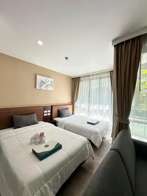 a hotel room with two beds and a window at Condominium Royal Lee Airport Phuket30 in Ban Bo Han