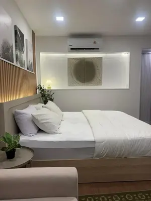 a bedroom with a white bed with a tv on the wall at Rinda House Patong 31 in Patong Beach