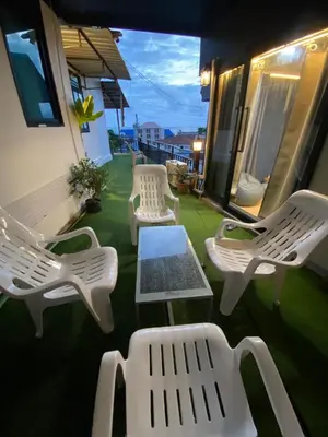 a group of white chairs and a table on a balcony at Rinda House Patong 31 in Patong Beach