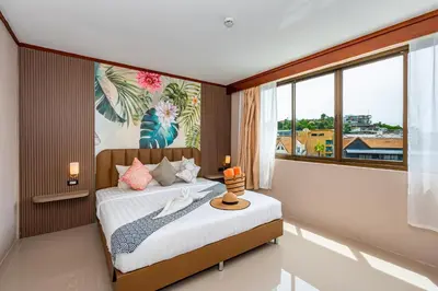 a bedroom with a bed and a large window at The Outdoor Kata Hotel in Kata Beach