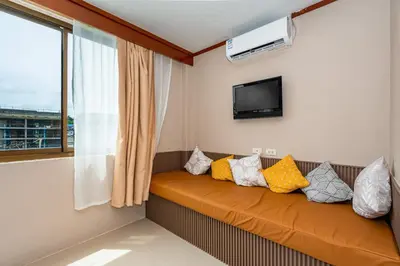 a room with a couch with pillows and a tv at The Outdoor Kata Hotel in Kata Beach