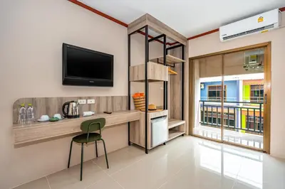 a room with a desk with a television and a chair at The Outdoor Kata Hotel in Kata Beach