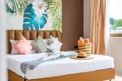a bedroom with a bed with a hat and pillows at The Outdoor Kata Hotel in Kata Beach