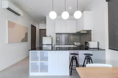 a kitchen with white cabinets and a black counter top at V242 Prime Location 2BR with Pool&Garden Near Beach in Bang Tao Beach
