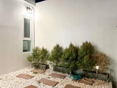 a courtyard with trees in a building with a window at Modern House in Phuket Town in Ban Na Khua