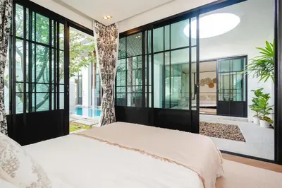 a bedroom with glass doors and a tree in the middle at MONO Villa Bang Tao 3 bedroom modern pool villa in Ban Pak Lak