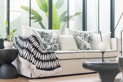 a living room with a white couch with pillows at MONO Villa Bang Tao 3 bedroom modern pool villa in Ban Pak Lak