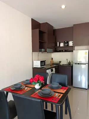 a kitchen with a table with plates and flowers on it at A Big Condo in Karon Walking distance to Beach in Karon Beach