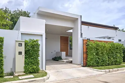 a white house with a hedge in front of it at Villa Botanica Modern Loft 2 in Ban Tha Rua