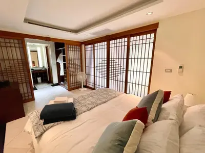 a large white bed in a room with a balcony at Kata Eden View - 1 BR Beachfront Luxury Apartment in Karon Beach