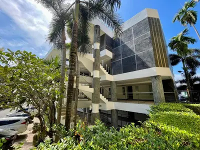 a building with palm trees in front of it at Kata Eden View - 1 BR Beachfront Luxury Apartment in Karon Beach