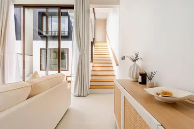 a living room with white walls and a staircase at Qabalah by Villacarte in Ban Pak Lak