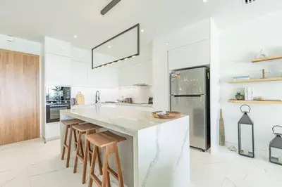 a white kitchen with a large island with stools at Beautiful Andamaya sea view in Ban Thalat Choeng Thale