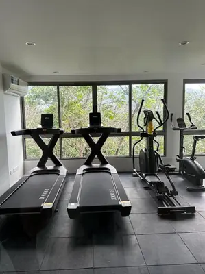 a gym with several treadmills and a table in a room at Fantasea Condo Kamala in Kamala Beach