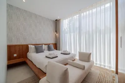 a bedroom with a white bed and two chairs at 3bdr New Luxury Villa Bang Tao by CapitalPro ASH-06 in Ban Phru Champa