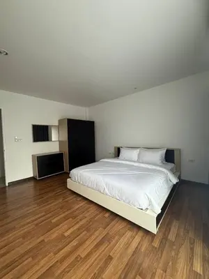 a bedroom with a large white bed and wooden floors at Town House European Style in Ban Ket Ho