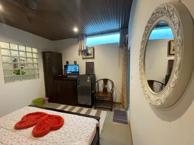 a bedroom with a bed and a mirror and a television at The Buddha Rawai Villa in Ban Saiyuan (1)