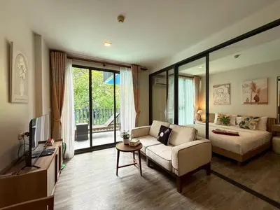 a living room with a couch and a tv at The Deck Patong Phuket by Mickey in Patong Beach