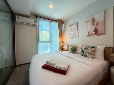 a bedroom with a large white bed with towels on it at The Deck Patong Phuket by Mickey in Patong Beach